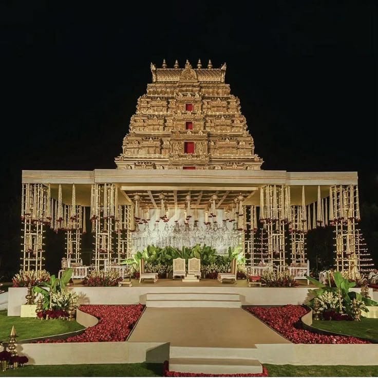Illuminated South Indian temple gopuram wedding stage with a floral carpet aisle by RAW Group